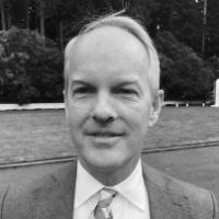 A man in a suit and tie standing outdoors, black and white photo.