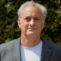 A man in a gray blazer standing outdoors.