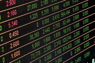 Stock market board displaying various numbers and symbols in green and red. image link to story