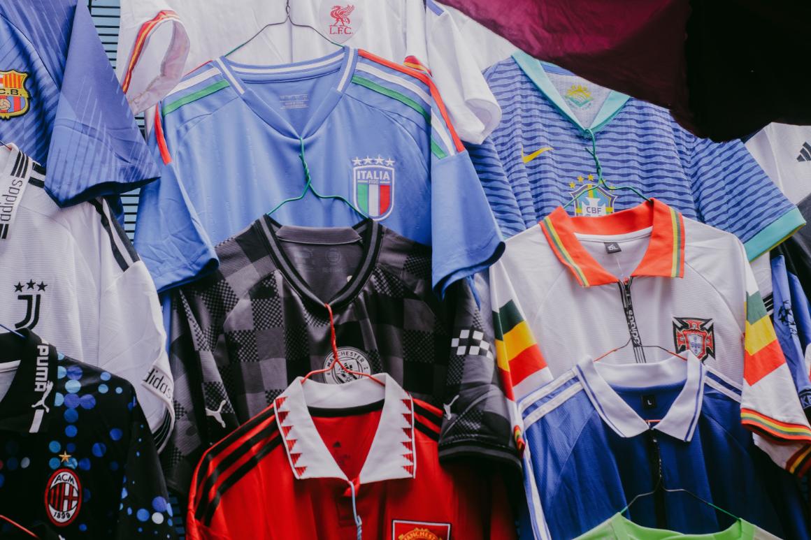 A colorful display of soccer jerseys hung on a line, featuring various national teams and clubs, including Italy, Brazil, and Germany.