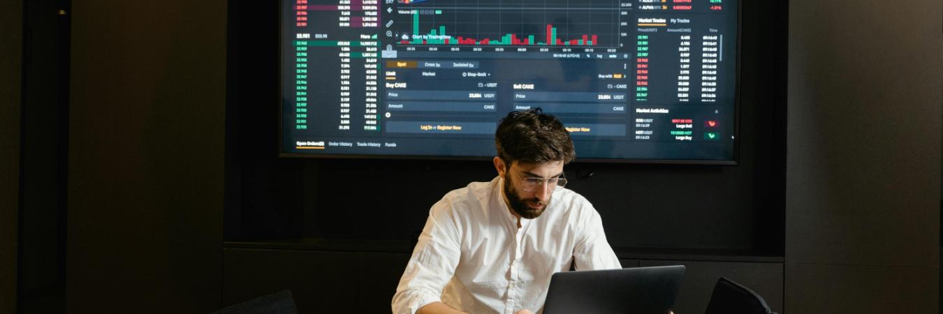 Economist working on laptop with graphs in background