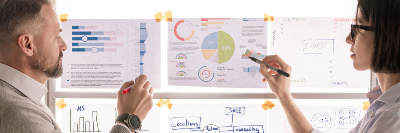 Business professionals discussing graphs taped to window