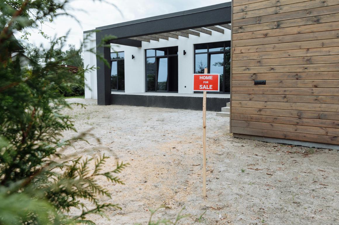 Home for sale sign in front of a new build house