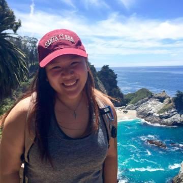A person in a red cap standing by the seaside.