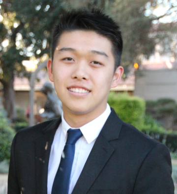 Bryan in a suit and tie, standing outdoors.
