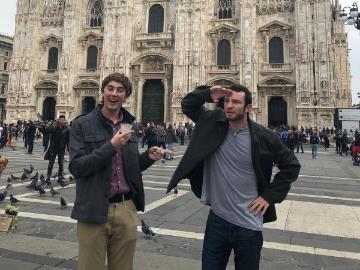 Two people in front of a large historic building.