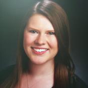 A person smiling against a dark background.