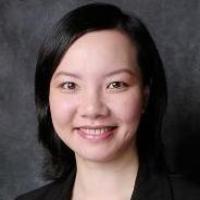 A person smiling in professional attire against a dark background.