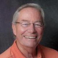 A person smiling, wearing an orange shirt.