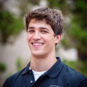 Alt text: Smiling person in a dark blue shirt outdoors.