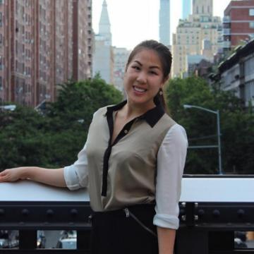 A person standing outside with city buildings in the background.