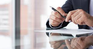 Person in suit holding a pen and paper during an interview.