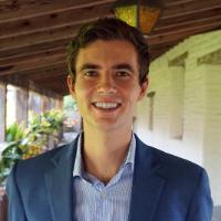 A person in a blue blazer standing in a covered walkway.