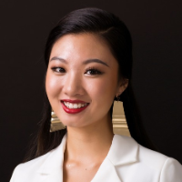 A woman in a white blazer with long earrings smiling.
