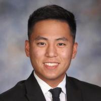 A person in a suit and tie smiling in a portrait.