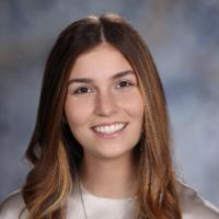 A person smiling against a blurred background.