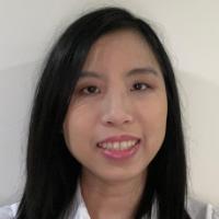 A woman smiling, wearing a white shirt against a plain background.