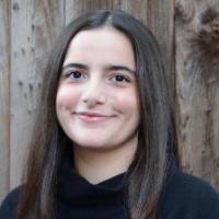 Person smiling in front of a wooden fence.