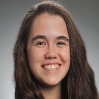 A person smiling with a grey background.