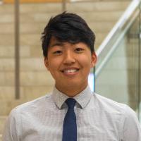 A person in a shirt and tie standing in front of stairs.