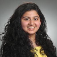 Headshot of Mallika Yeleswarapu smiling in professional attire with gray background.