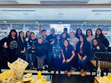 Group of people posing in front of a San Jose Sharks game.