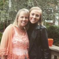 Two people standing together, smiling, on a wooden deck.
