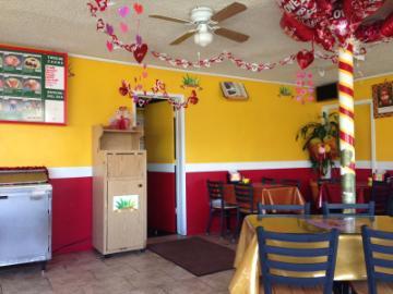 A colorfully decorated interior with yellow and red walls, plants, and seating area.