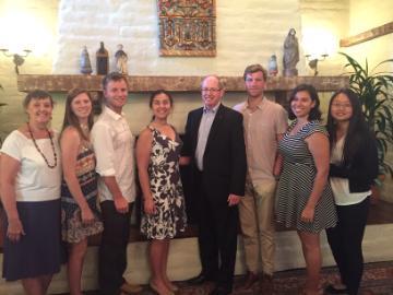 Alt text: Group of seven people posing indoors with Fr. Engh in 2017.