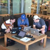 Several people sitting on outdoor furniture outside a building.
