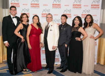 Group of people posing at Hispanic Foundation Gala against step and repeat banner.