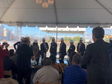 A group of people standing under a tent at a ceremony.