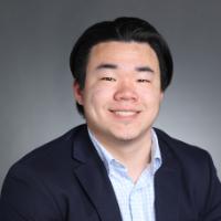 A man smiling in a formal portrait setting.