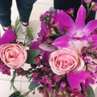 A bouquet featuring pink and purple flowers held by an unseen person.