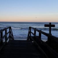Wooden walkway leading to Pajaro Dunes beach with waves in the background.