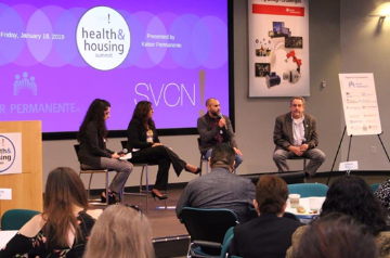 Panel discussion at SVCN event with four speakers and an audience.