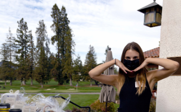 A person outdoors posing with a black mask.