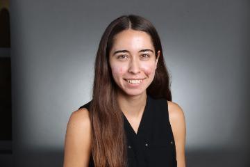 A smiling person with a dark background.