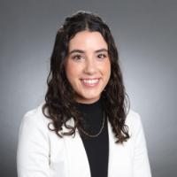 A person in a white blazer and black top smiling.