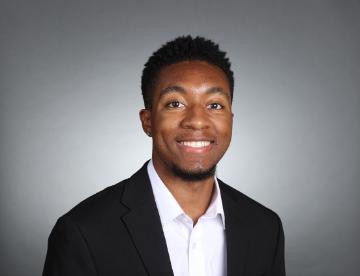 A person in a suit with a grey background.