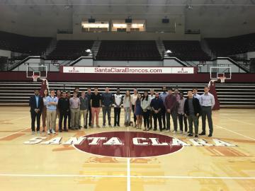 Group photo in a sports arena with a 'Sports Business Club' banner.