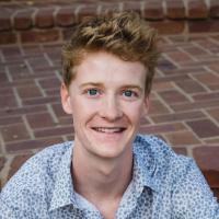 A person sitting on brick steps, smiling, titled Cole Normandin.