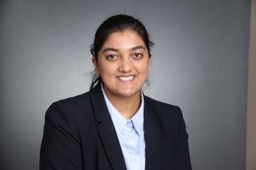 A person in a suit against a gray background.