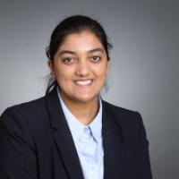 A person in a suit against a gray background.