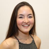 A smiling woman in polka dot top against a light background.