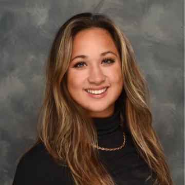 A person smiling in front of a grey background.