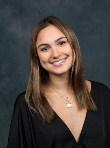 A person smiling against a dark studio background.