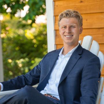 A person in a suit sitting on a porch chair.