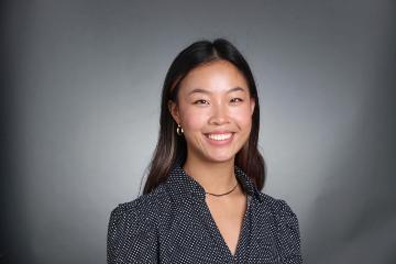 A person smiling against a gray background.