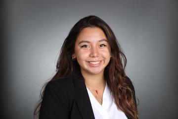 A woman in a black blazer smiles in a headshot photo.